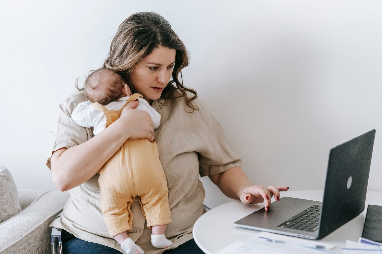 Mum holding baby while working on a laptop